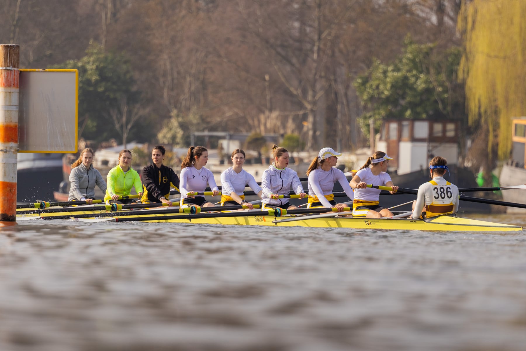 A yellow rowing shell racing low across the water at Head of the River.