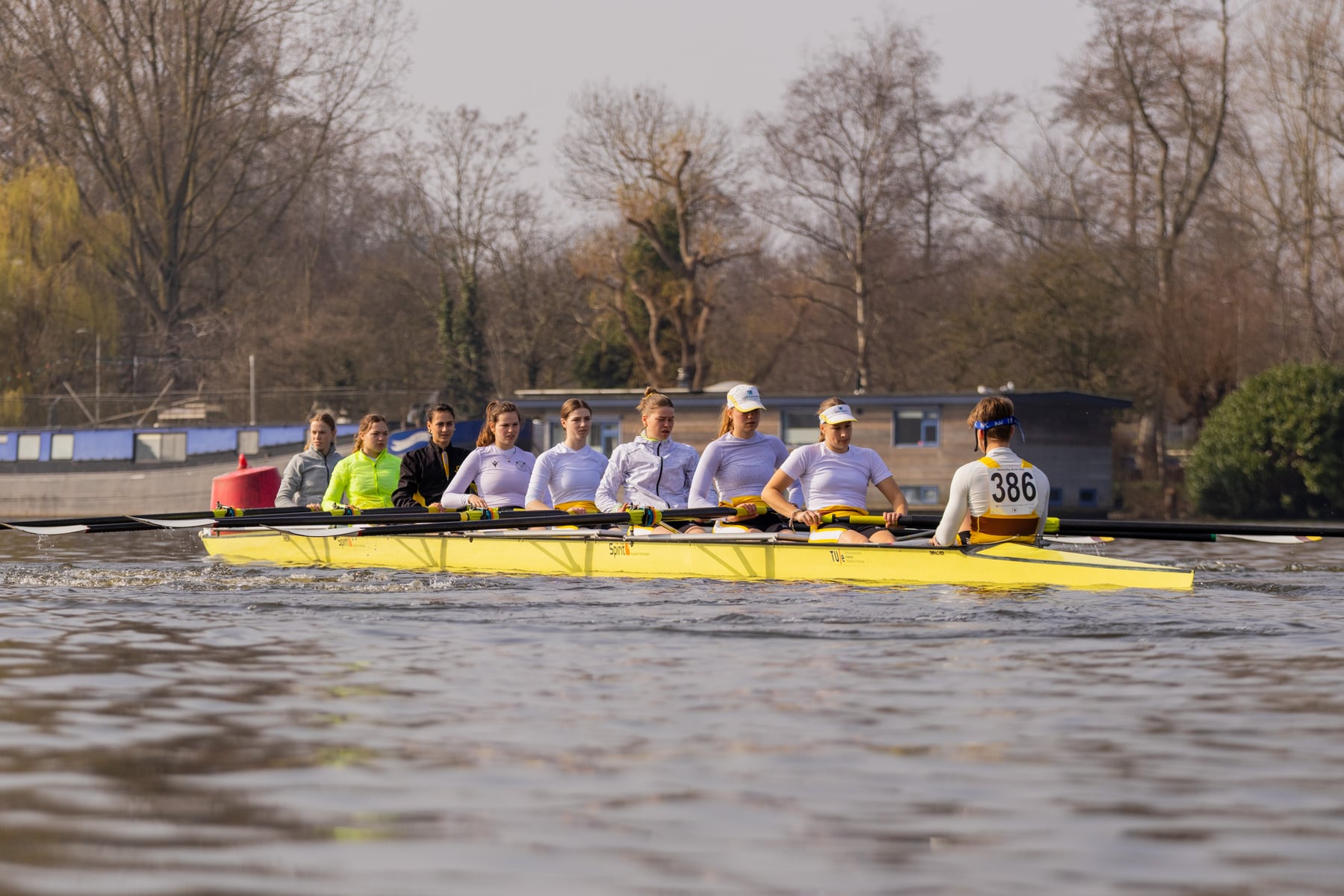 A full crew passing the riverbank during a Head of the River race.
