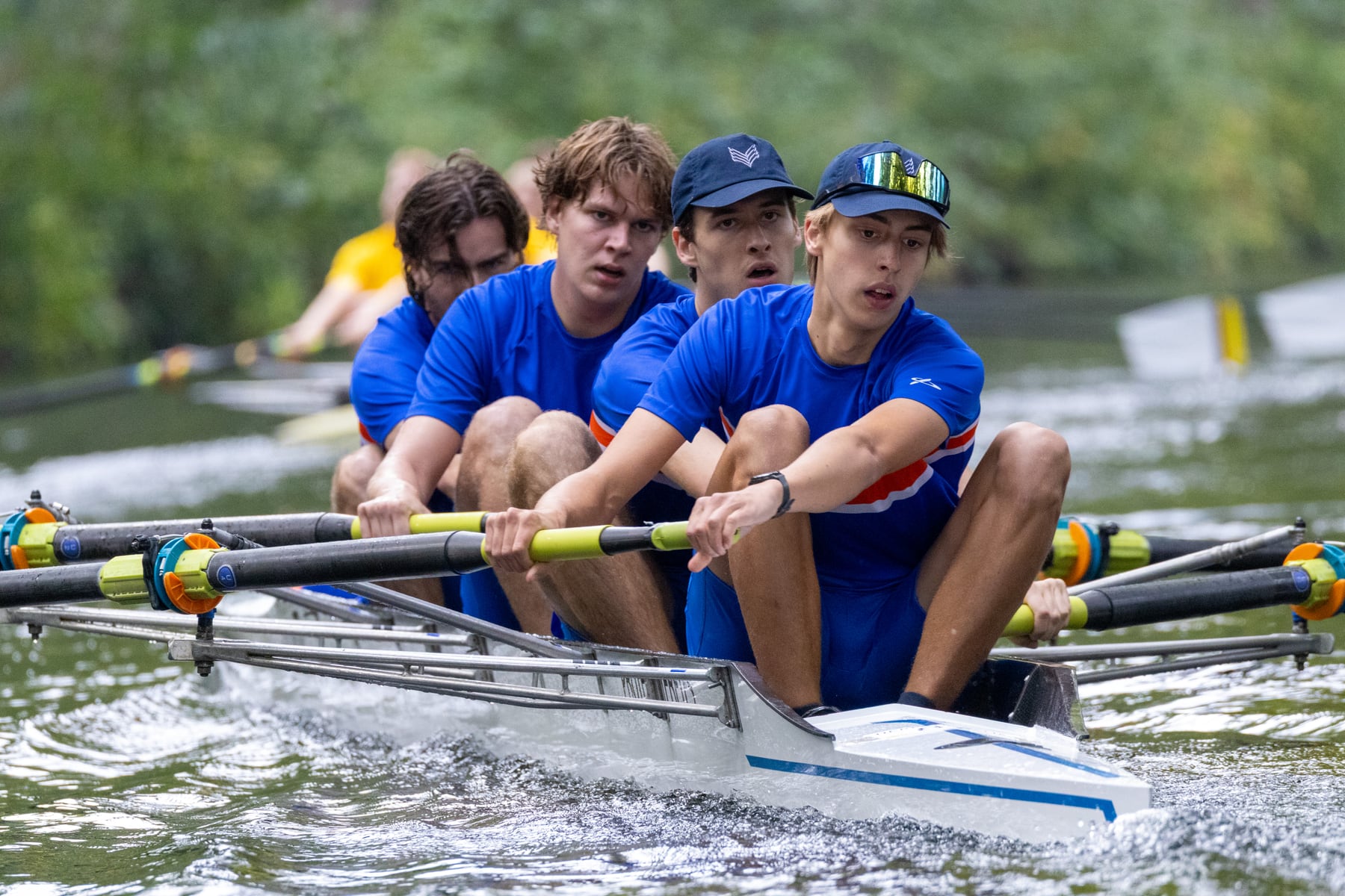 A blue crew driving through the water in tight formation during racing.