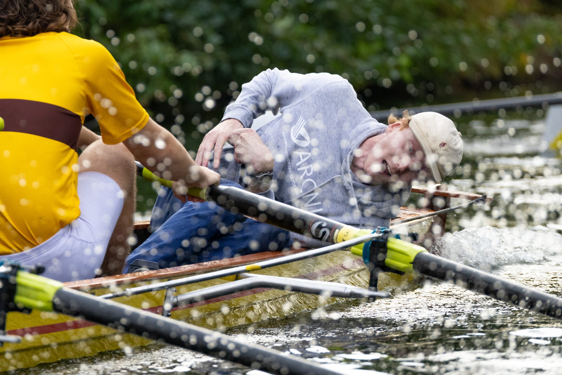 Close race detail of oars, hands, and water splashing over the shell.