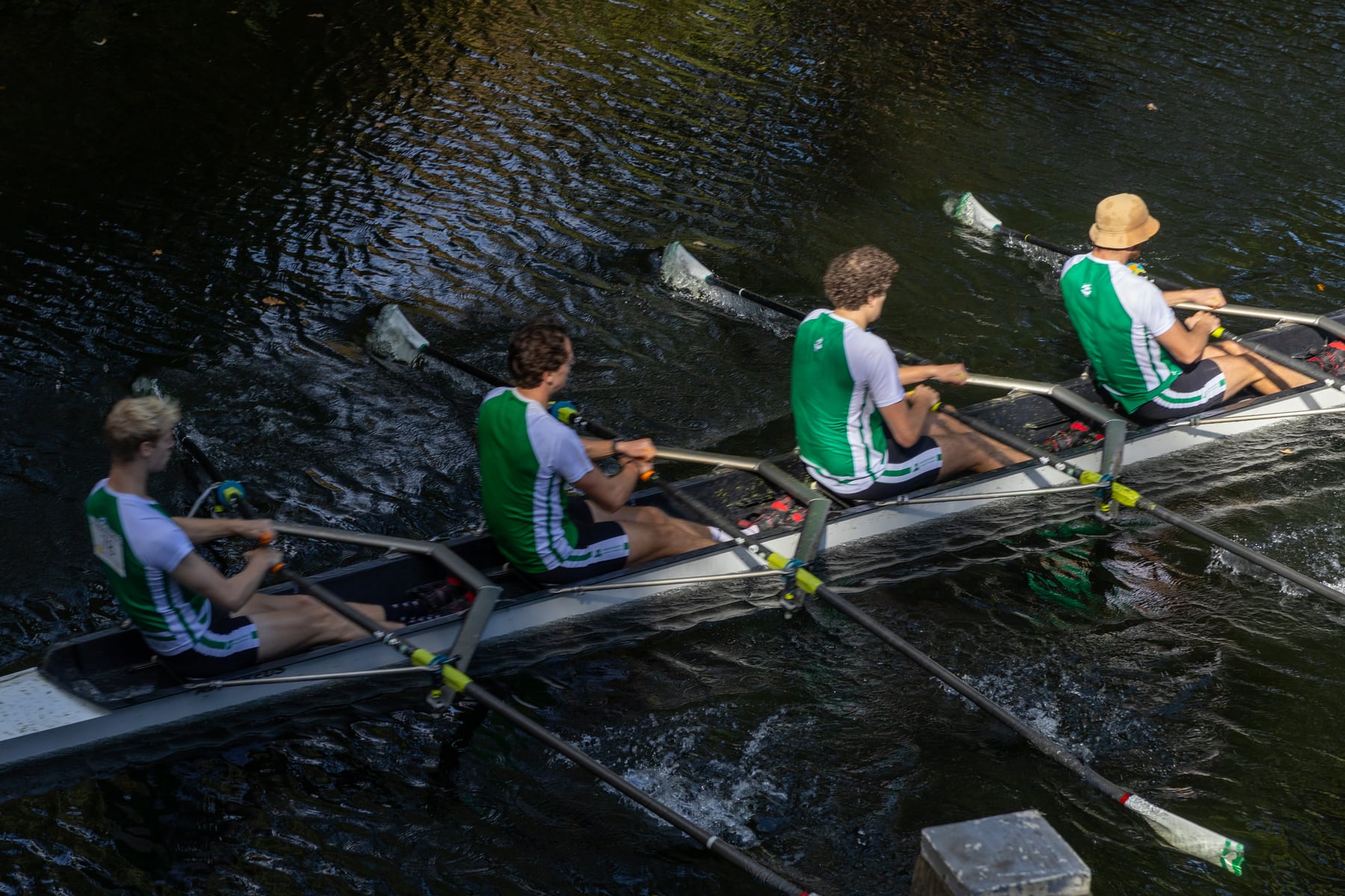 A green crew and blue crew crossing paths in a high-angle regatta view.