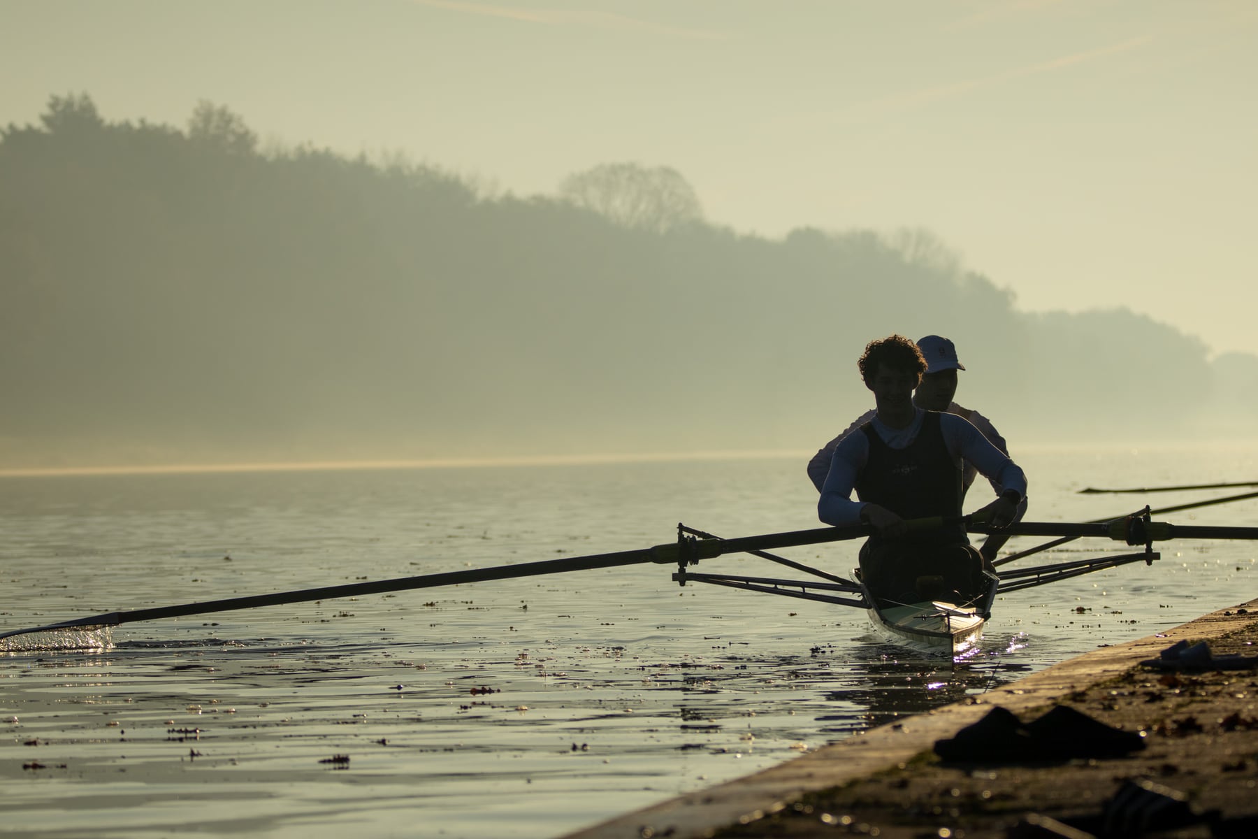 A rower framed in silhouette on still morning water in Tilburg.