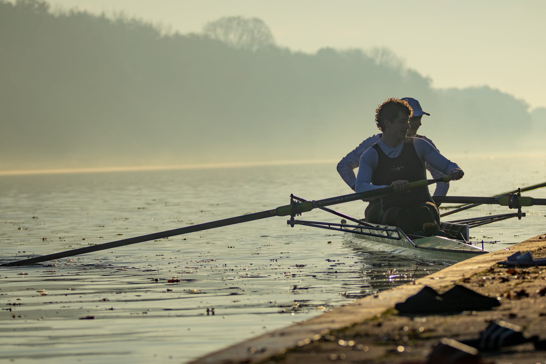 A single rower silhouetted against misty golden water in Tilburg.